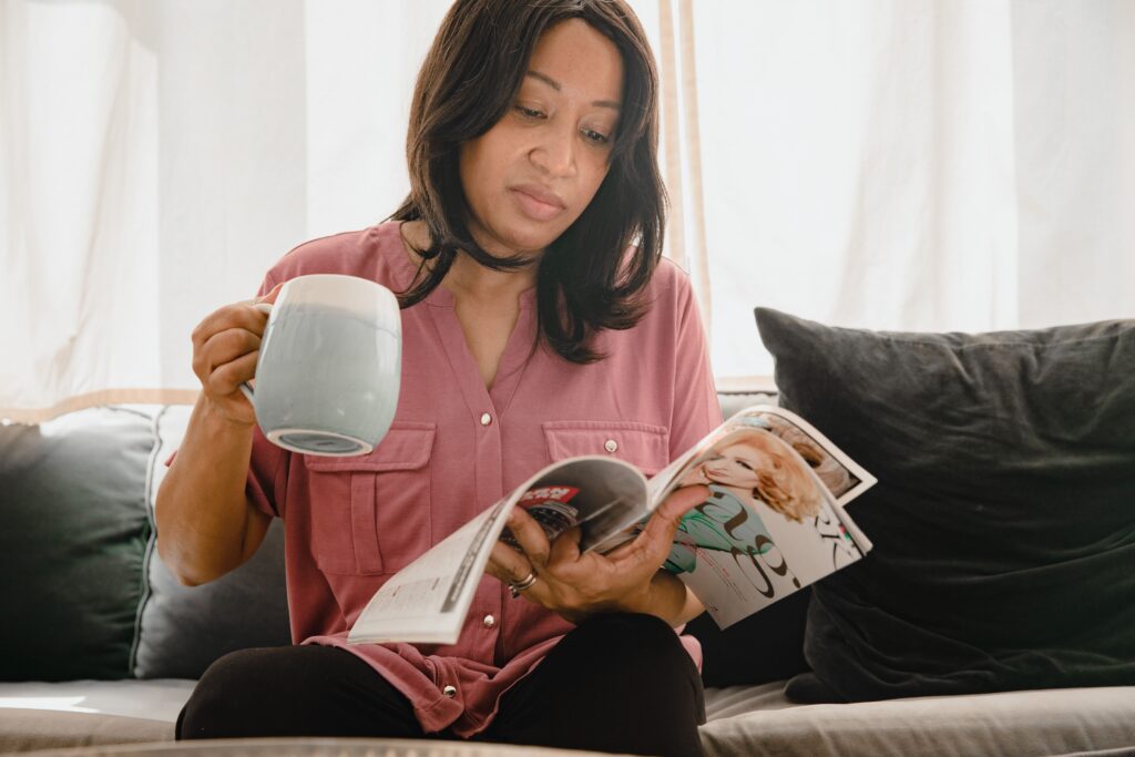 Mulher madura tomando café e lendo revista tranquila em casa